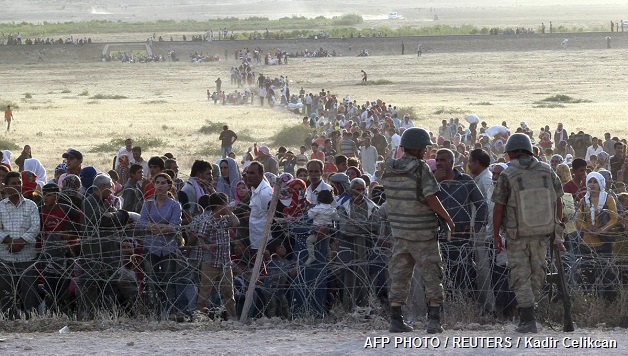 Syria crisis - Turkish troops on standby while the Syrian people waiting behind the border fence near the town Suruc, the province of Sanliurfa, Turkey, Thursday (18/9). Islamic State of rebels occupying a Kurdish city in northern Syria on Thursday after seizing 21 villages in a large-scale attack, prompting the military actions of Kurdish troops in neighboring Turkey urged his followers to help counter the militant attack. The attack in the town of Ayn al-Arab, or what is known as the city of Kobani in Kurdish, comes two days after a senior US military official said that the Syrian opposition will probably need the help of Syrian Kurds to defeat the Islamic State. About 3,000 men, women, and children arrived at the Turkish border which is around 10km from Kobani but is still waiting on the Syrian side after nightfall. AFP PHOTO / REUTERS / Kadir Celikcan