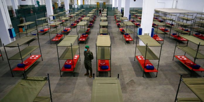 Coronavirus_Spanish_State A Spanish soldier standing next to beds set up at a temporary hospital for vulnerable people in Barcelona. PAU BARRENA/AFP via Getty Images